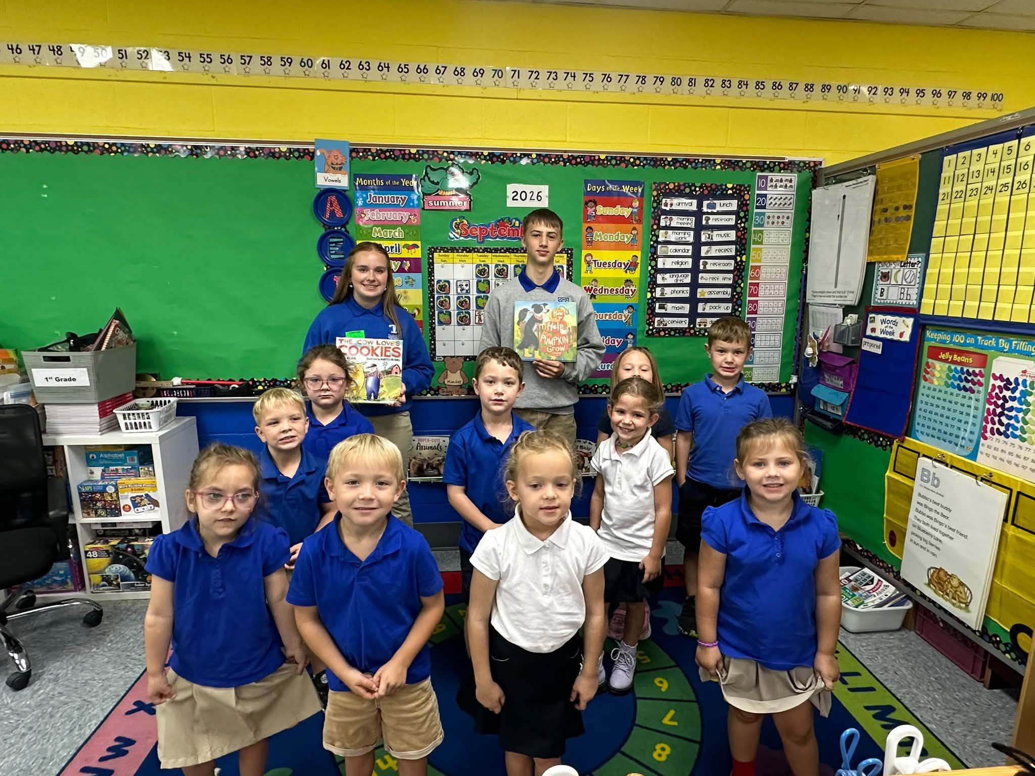 Younger and older students gather with picture books in a classroom.