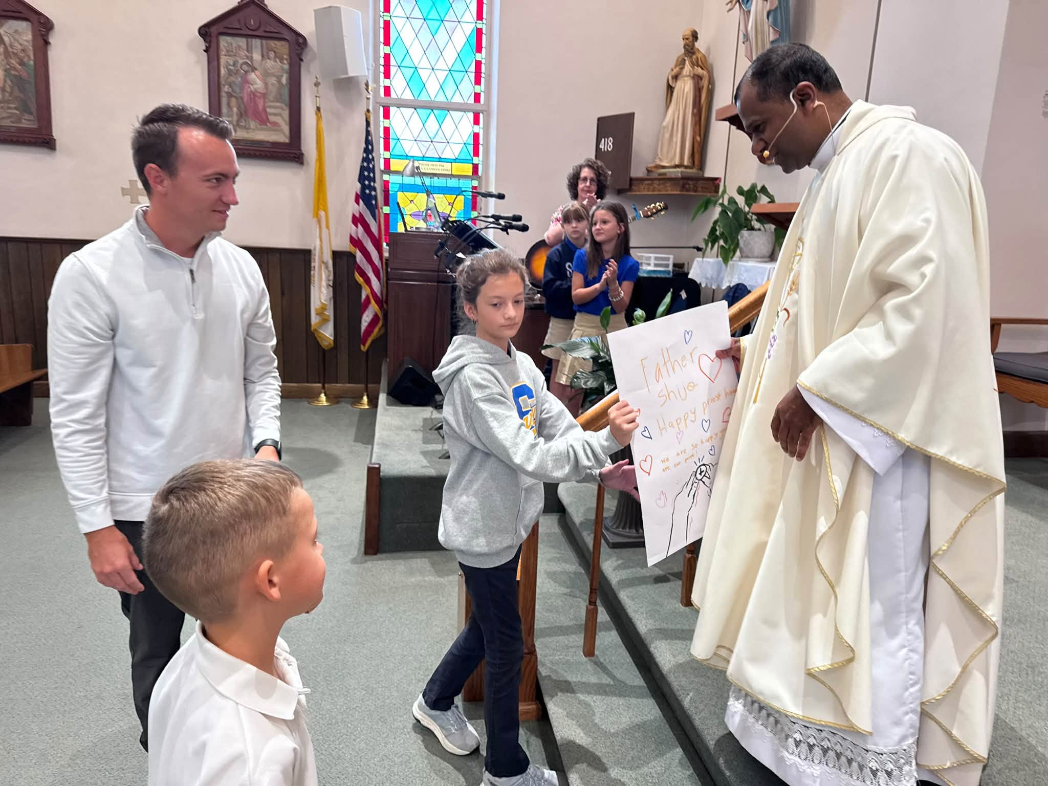 Students present a handmade card to a priest inside the church.