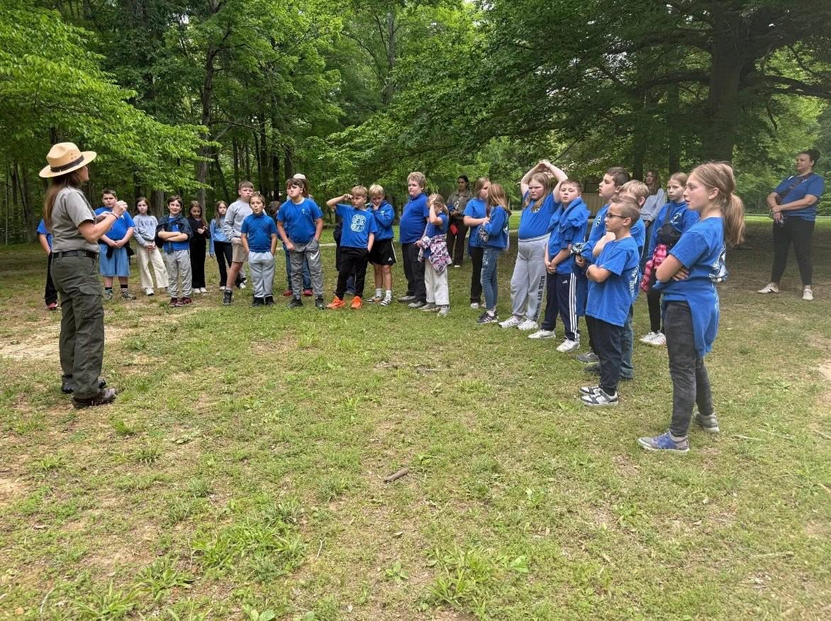 Students listen to a guide during an outdoor learning visit.